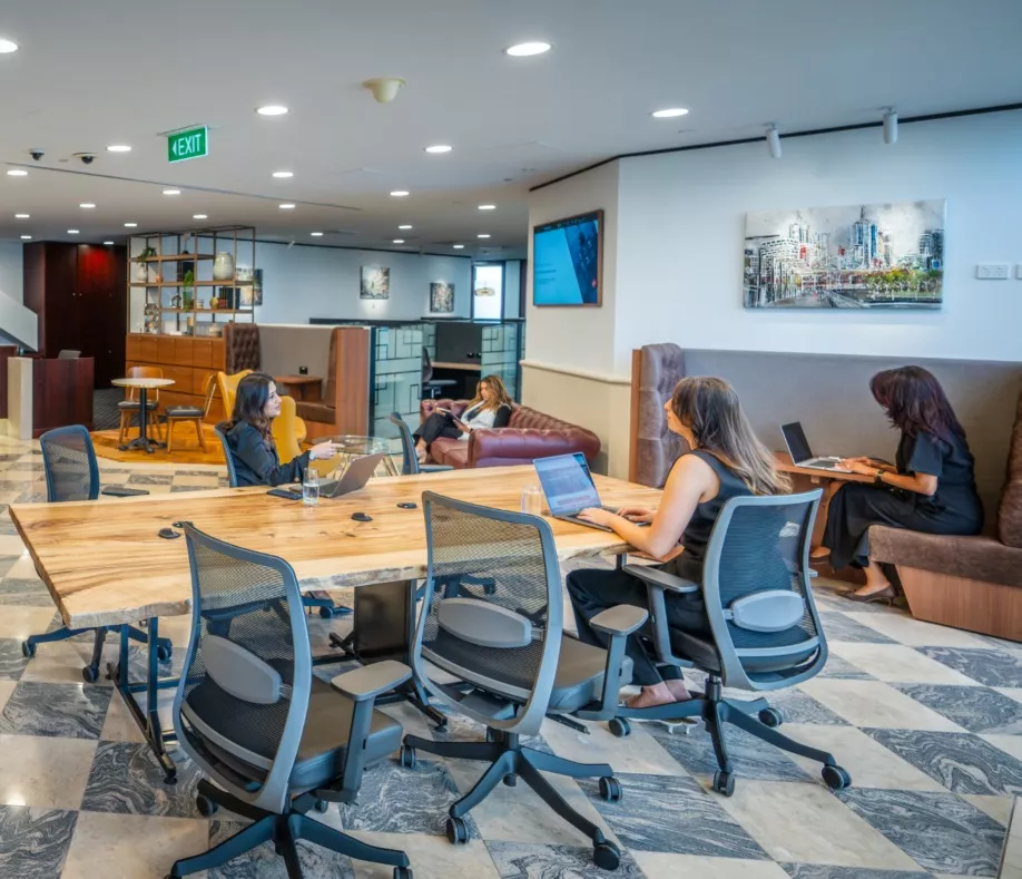 Clients working in a long table in a modern coworking space and enjoying the lounge in Servcorp 140 William, Melbourne
