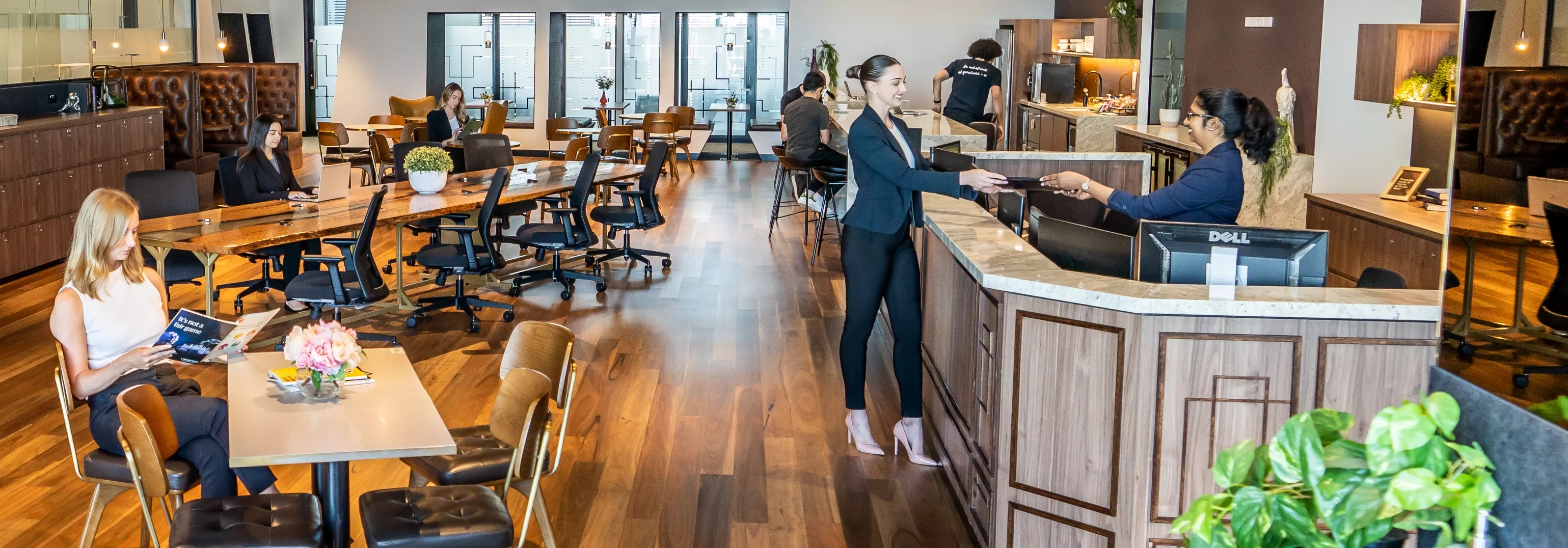 Clients working in a modern coworking space and receptionist helping a client in Servcorp 100 Mount Street