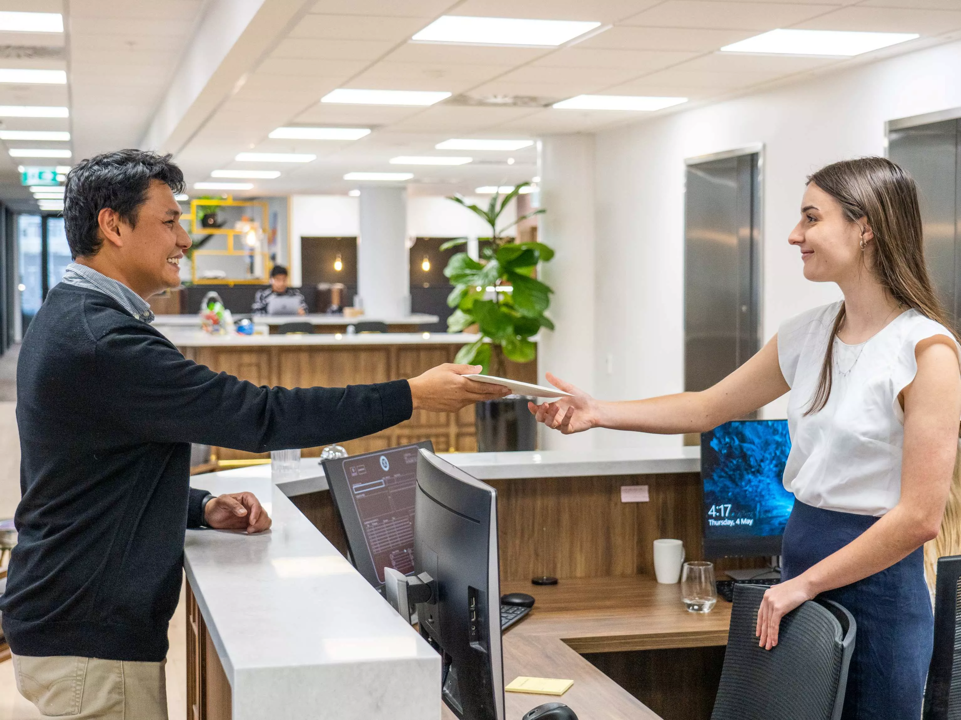 Dedicated receptionists helping a client, delivering a parcel in the modern coworking space of Servcorp Bell Gully Building, Wellington