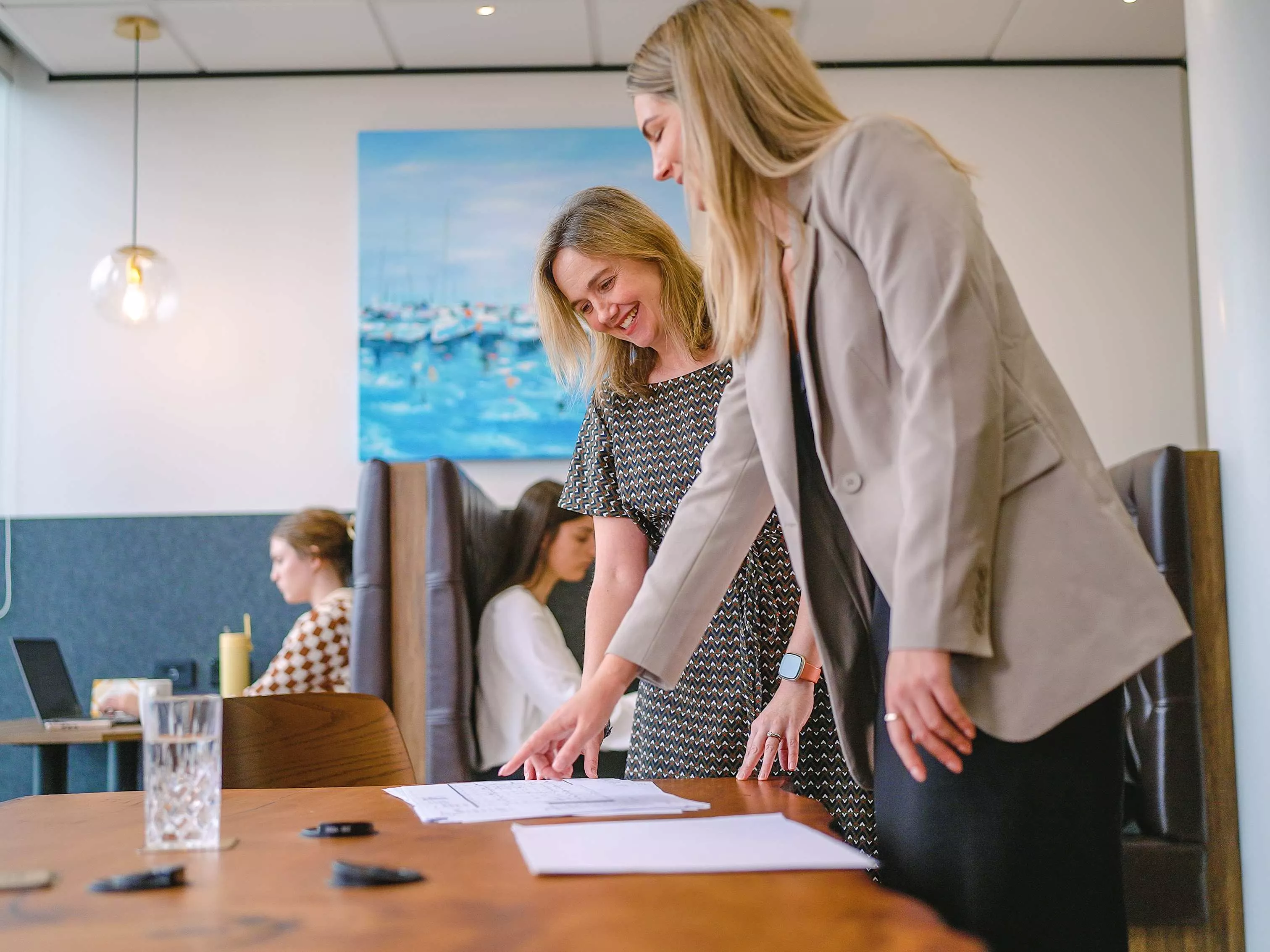 Close up on clients working in a modern coworking shared space on a long table with great booths in Servcorp Bell Gully Building, Wellington