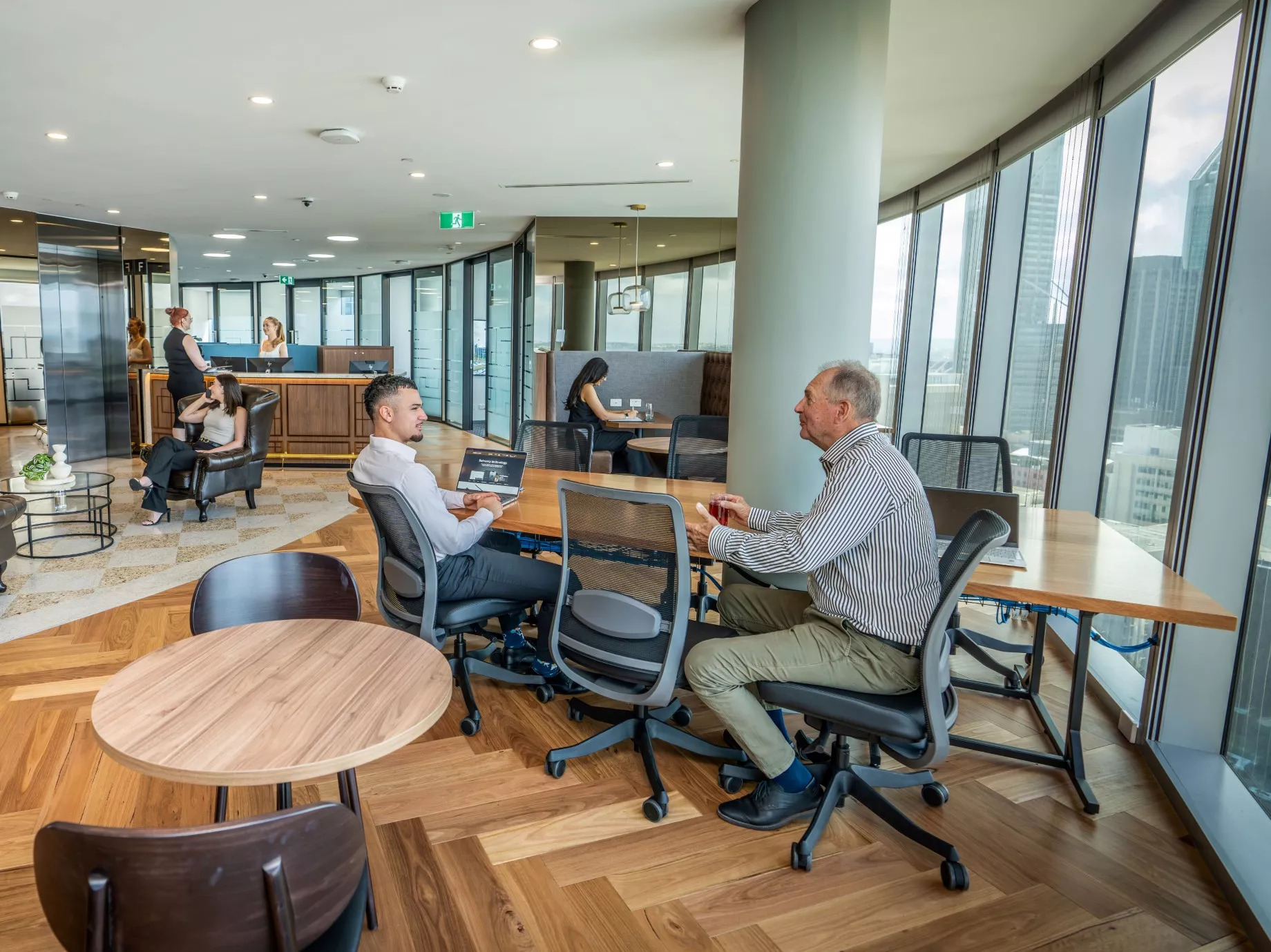 Clients working in a modern coworking space on a long table, enjoying the lounge in Servcorp Capital Square Tower 3 Perth